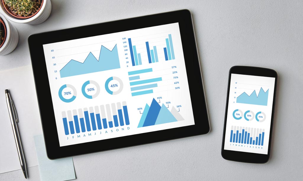 A desk with screens showing infographic progress charts