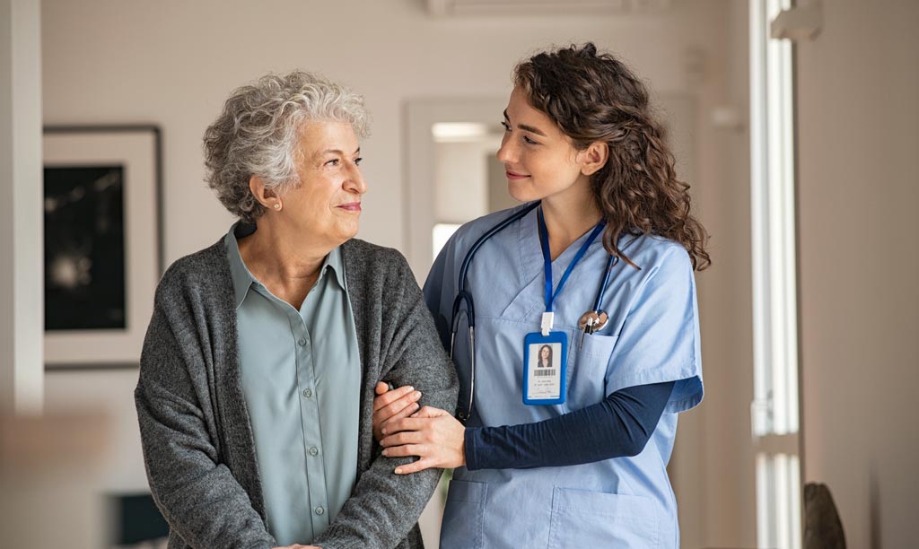 Nurse smiling while assisting her patient at nursing home